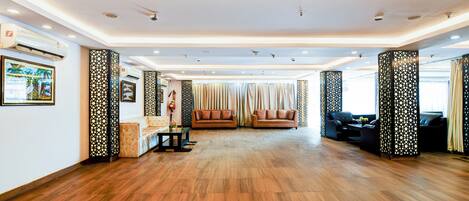 A spacious lobby with wooden flooring, two sofas, a coffee table, and decorative panels.