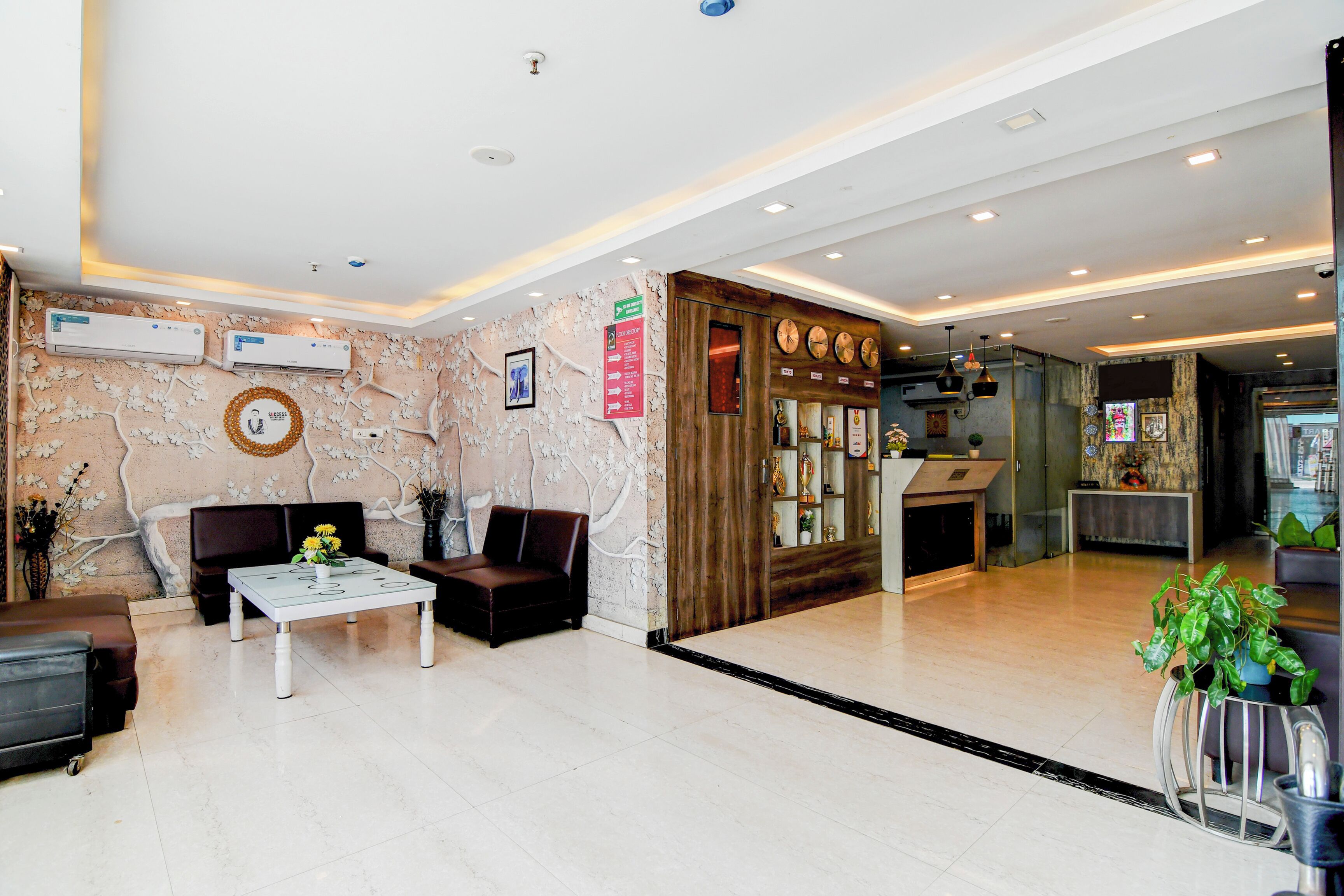 A lobby with a reception desk, seating area, and a wall with clocks.