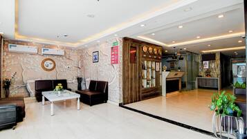 A lobby with a reception desk, seating area, and a wall with clocks.