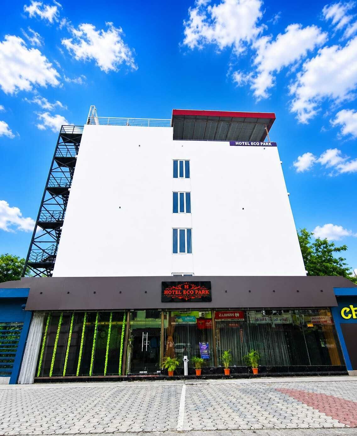 Un hôtel à la façade blanche, au toit rouge, et sur lequel on peut lire l’inscription « HÔTEL ECO PARK ».