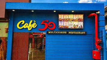 A blue building with a sign reading 'Café 59 MULTICUISINE RESTAURANT' and a menu board above the entrance.