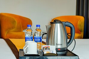 A hotel room with a bed, a tray with a coffee pot, two water bottles, a mug, and a tray of breakfast items. - Hotel Eco Park by Carlton Suites (Barasat)