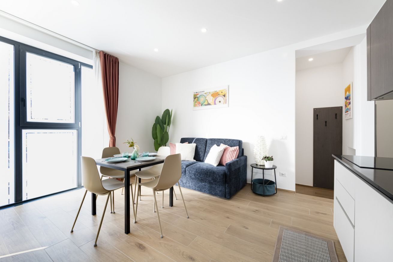 A modern living room with a dining area, a sofa, and a kitchen area.