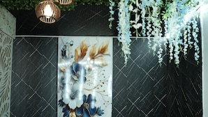 Ein Zimmer mit weißen Korbmöbeln, einer Wand mit floralem Dekor und hängenden weißen Blüten.