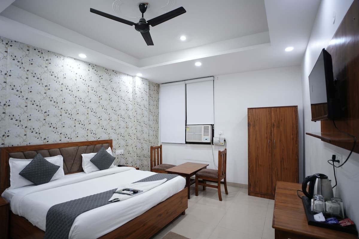 Ein Hotelzimmer mit Bett, Schreibtisch, Stuhl, Kleiderschrank und Deckenventilator.