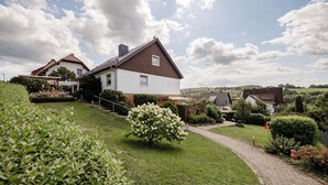 A residential area with a well-maintained lawn, a paved pathway, and houses with distinct architectural styles. - Apartment Balogh - Welcome to the Harz Mountains - because your vacation starts here ✓ (Osterode am Harz)