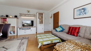 A living room with a sofa, a coffee table, a television, and a bookshelf. - Apartment Balogh - Welcome to the Harz Mountains - because your vacation starts here ✓ (Osterode am Harz)
