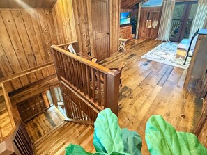 A wooden interior with a staircase, a television, and a view of the outdoors. - Bear Cove - rustic mountainside cabin with incredible view + free train tix (Bryson City)
