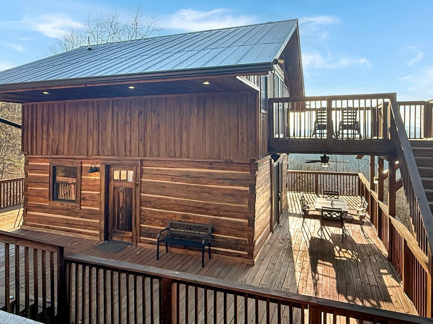 A wooden cabin with a deck and a balcony.