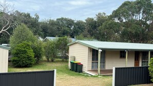 A small, single-story house with a green roof, a porch, and a fenced yard. - 700m to Surf Beach•Relaxed Family Coastal Escape for 5•Linen provided (Venus Bay)