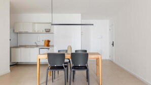 Una cocina moderna con armarios blancos, una mesa de comedor de madera y sillas negras.