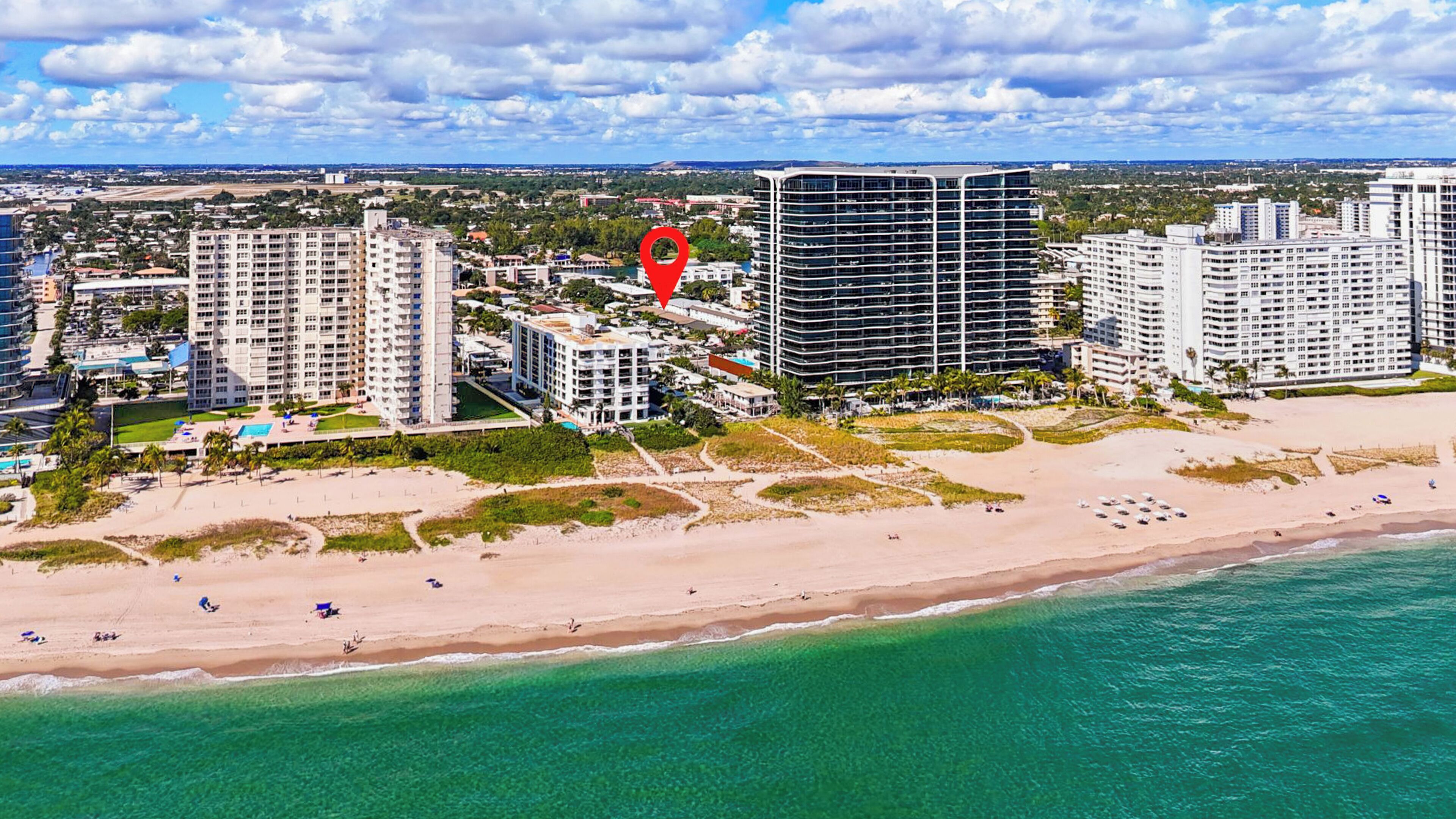 A coastal cityscape with high-rise buildings, a beach, and clear skies.