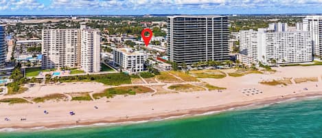 A coastal cityscape with high-rise buildings, a beach, and clear skies.