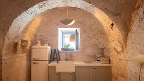 A rustic kitchen with a stone archway, a vintage blender, a wooden chair, and a window with a view. - Private Villa with WIFI, private pool, hot tub, A/C, TV, patio, panoramic view, close to Ostuni (Martina Franca)