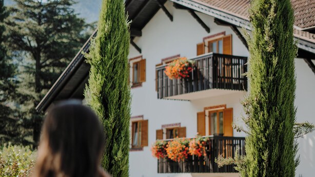 A two-story building with balconies, a garden, and a clear sky. - Waidmannhof (Merano)