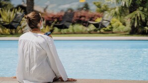 A person sitting by a pool with a mountainous landscape in the background. - Waidmannhof (Merano)