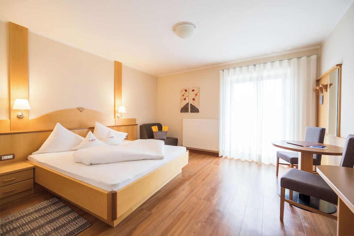 A hotel room with a bed, bedside tables, a desk, and a chair.