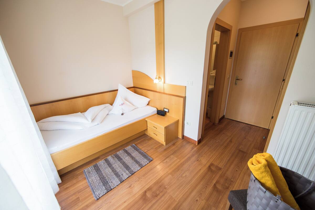 A bedroom with a bed, bedside table, and a small rug.
