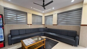 A waiting area with a sofa, a coffee table, and a ceiling fan. - GoHotels Shreenidhi Dwarka (Dwarka)