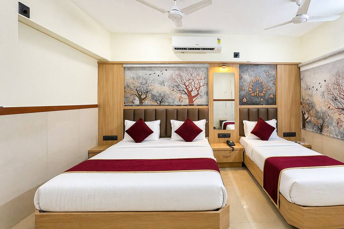 A hotel room with two beds, a mirror, a ceiling fan, and artwork on the walls.