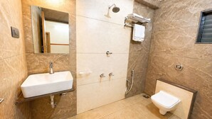 A bathroom with a sink, mirror, shower, and toilet. - GoHotels Shreenidhi Dwarka (Dwarka)