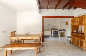 Una cocina amplia con una mesa y un banco de madera, salpicadero de azulejos blancos y armarios de madera.