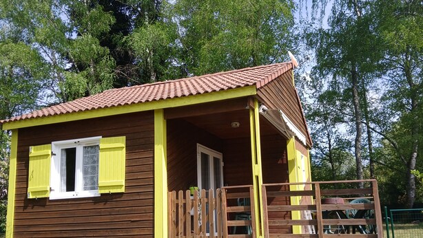 A small wooden cabin with a porch, a door, and a window with shutters.