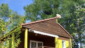A small wooden cabin with a porch, a door, and a satellite dish.