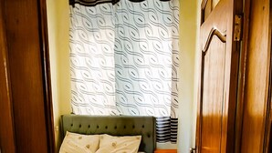 A bedroom with a bed, a nightstand, and a wardrobe. - Parkviewperch (Kigali)
