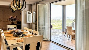 A dining area with a table set for four, a large chandelier, and a view of a patio with a chair. - Awesome home in Coin with private swimming pool, can be inside or outside (Coin)