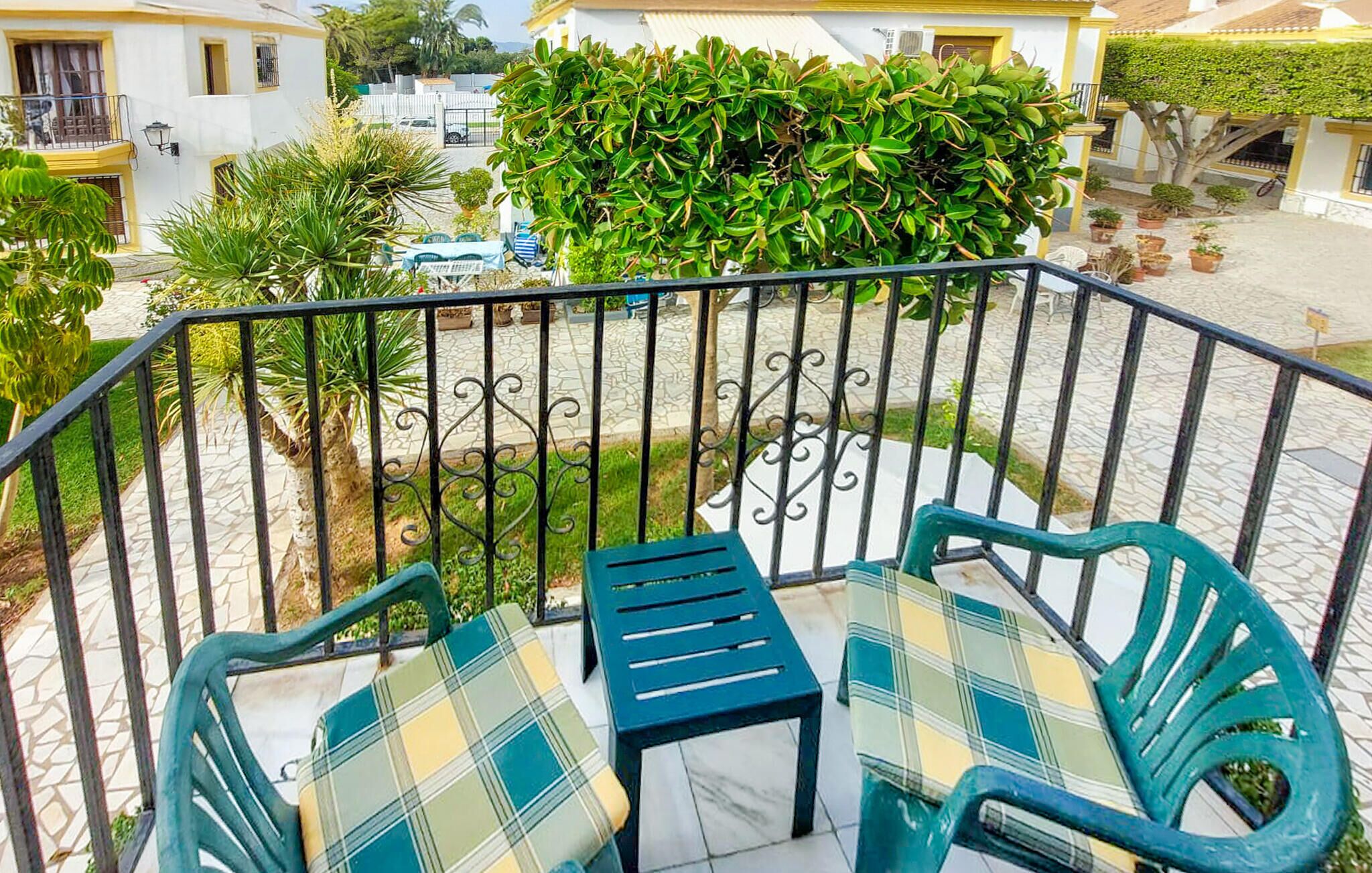 Un balcon avec deux chaises et une table, entouré d’une rambarde en métal.