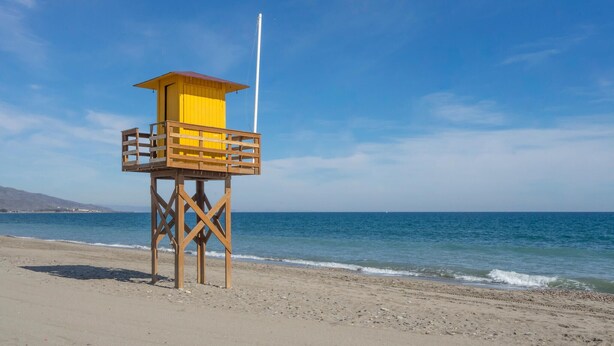 Ein Rettungsturm am Strand unter blauem Himmel.