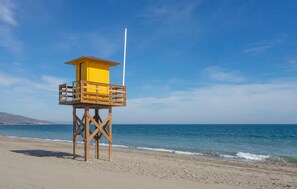 Ein Rettungsturm am Strand unter blauem Himmel.