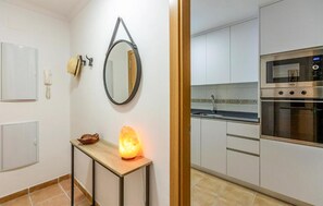 A modern kitchen with white cabinets, a stainless steel oven, and a small table with a salt lamp. - Stunning apartment in Itrabo with WiFi (Itrabo)