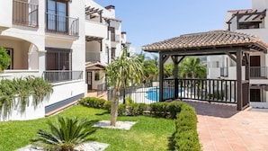 Um pátio com piscina, um gazebo e um jardim bem cuidado com diversas plantas.
