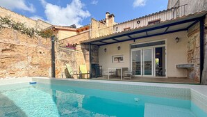 A swimming pool with a patio area, a stone wall, and a covered seating area. - Lovely home in Petra with private swimming pool, can be inside or outside (Petra)