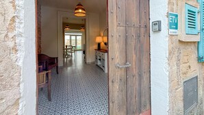 A rustic interior with a wooden door, a dining area with chairs, a table with a lamp, and patterned floor tiles. - Lovely home in Petra with private swimming pool, can be inside or outside (Petra)