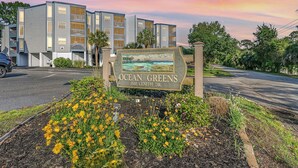Une enseigne pour Ocean Greens, située au 1500, avenue Centith, avec en arrière-plan un immeuble à plusieurs étages.