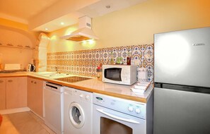 A compact kitchen with a washing machine, microwave, and stainless steel refrigerator. - Maison piscine proche mer (Portel Des Corbieres)