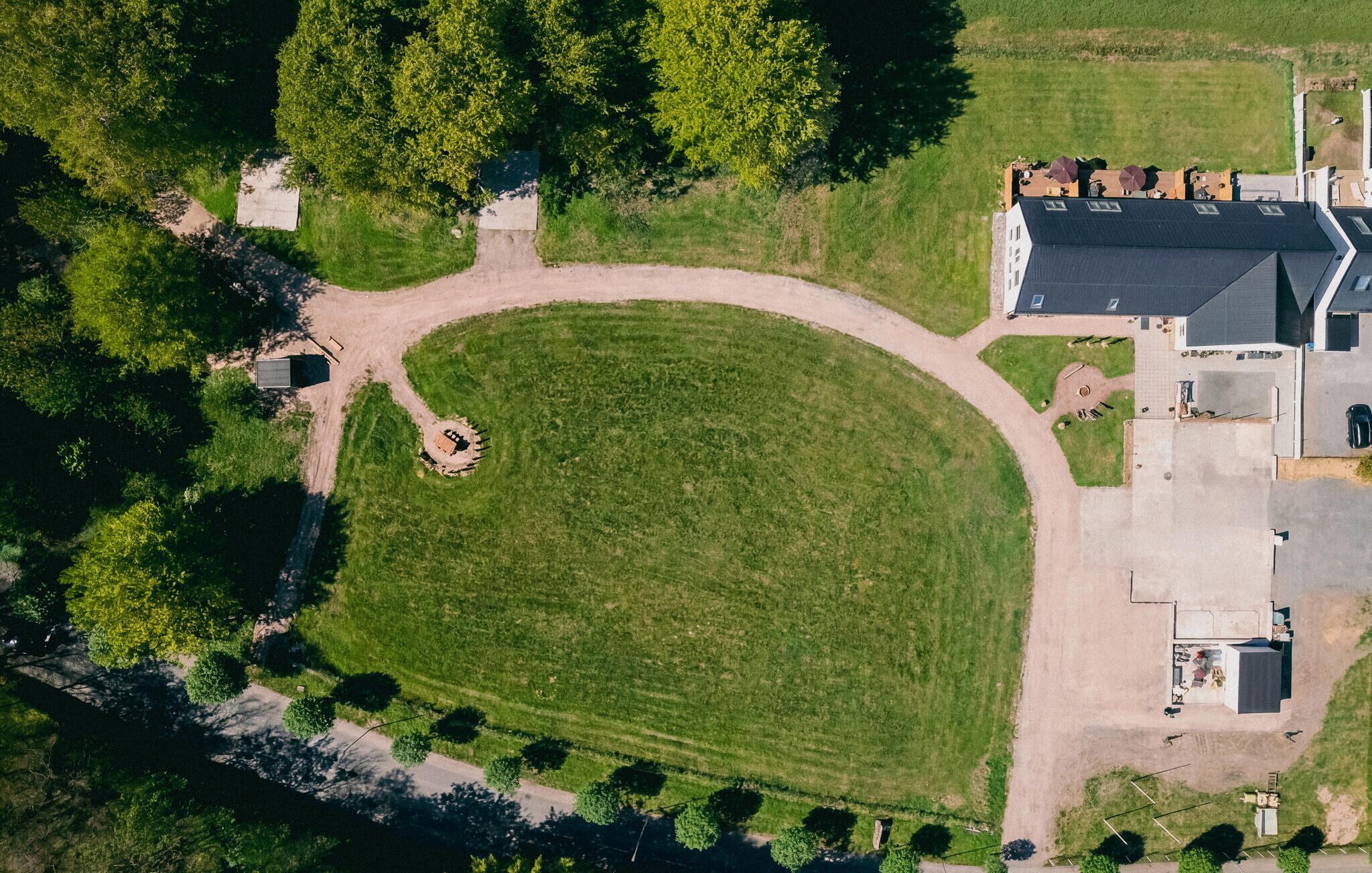An aerial view of a property with a large lawn, a circular driveway, and a building with a sloped roof.