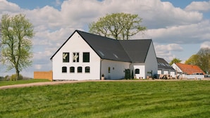 A white two-story house with a sloped roof, a visible front porch, and a well-maintained lawn.