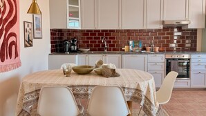 A kitchen with white cabinets, a brick backsplash, and a dining area with a table and chairs.