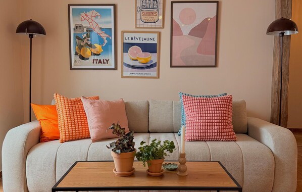 A living room with a sofa, two floor lamps, and a coffee table with potted plants.