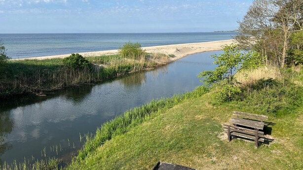 Vista al río con un banco y una playa de arena.