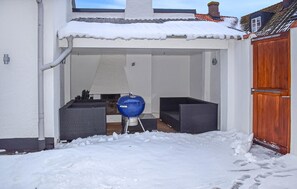 A covered outdoor area with a barbecue grill, seating, and a wooden door. - 3 bedroom nice home in Simrishamn (Simrishamn)