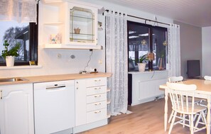 A modern kitchen with white cabinetry, a wooden countertop, and a dining area with a white table and chairs. - Beautiful home in Simrishamn (Simrishamn)