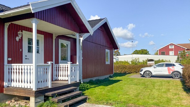Ein rotes Haus mit weißem Wintergarten und Stufen zum Eingang.