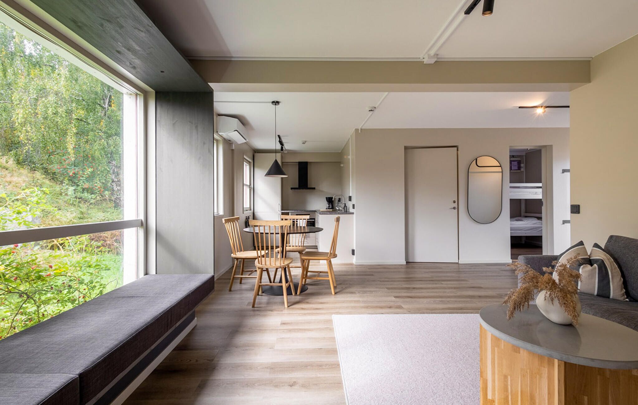 Un intérieur moderne comprenant un coin repas, une cuisine, un espace de vie et une vue sur la verdure.