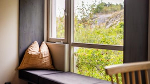 Un siège de fenêtre agrémenté de coussins, avec vue sur la verdure.