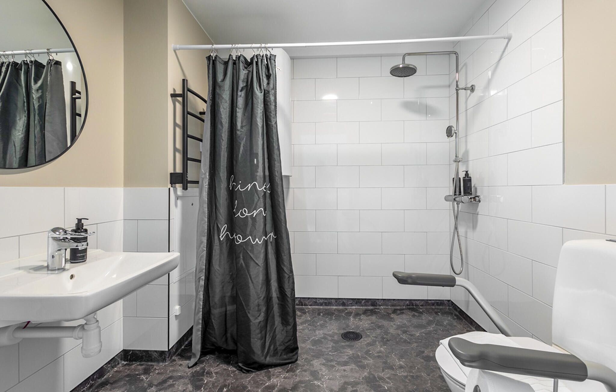 Et moderne badeværelse med bruser, toilet, vask og spejl.